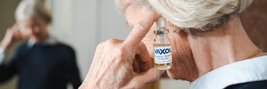 Kvinna som står framför en spegel och använder Vaxol.