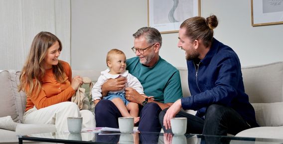 Familj sitter i soffan med ett litet barn.