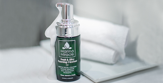 Grön flaska med ansiktsrengöring från Marina Miracle, placerad på en vit handduk.