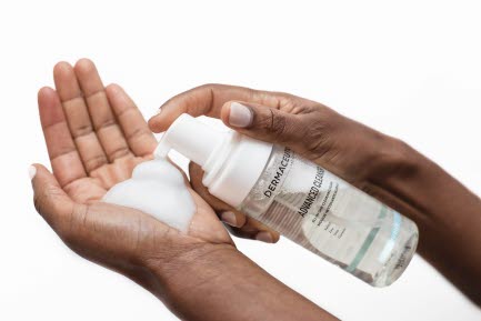 Bilden visar en person som pumpar ut ett lödder från en flaska Dermaceutic Advanced Cleanser i handen. Bakgrunden är vit.