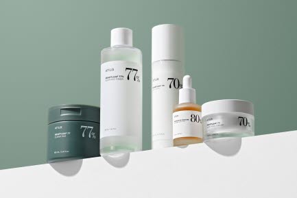 En uppsättning Anua hudvårdsprodukter på en vit yta framför en grön bakgrund. Produkten inkluderar ansiktskräm, serum, toner och en mask.